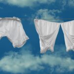 White vintage clothing drying on a clothesline with a blue sky background.